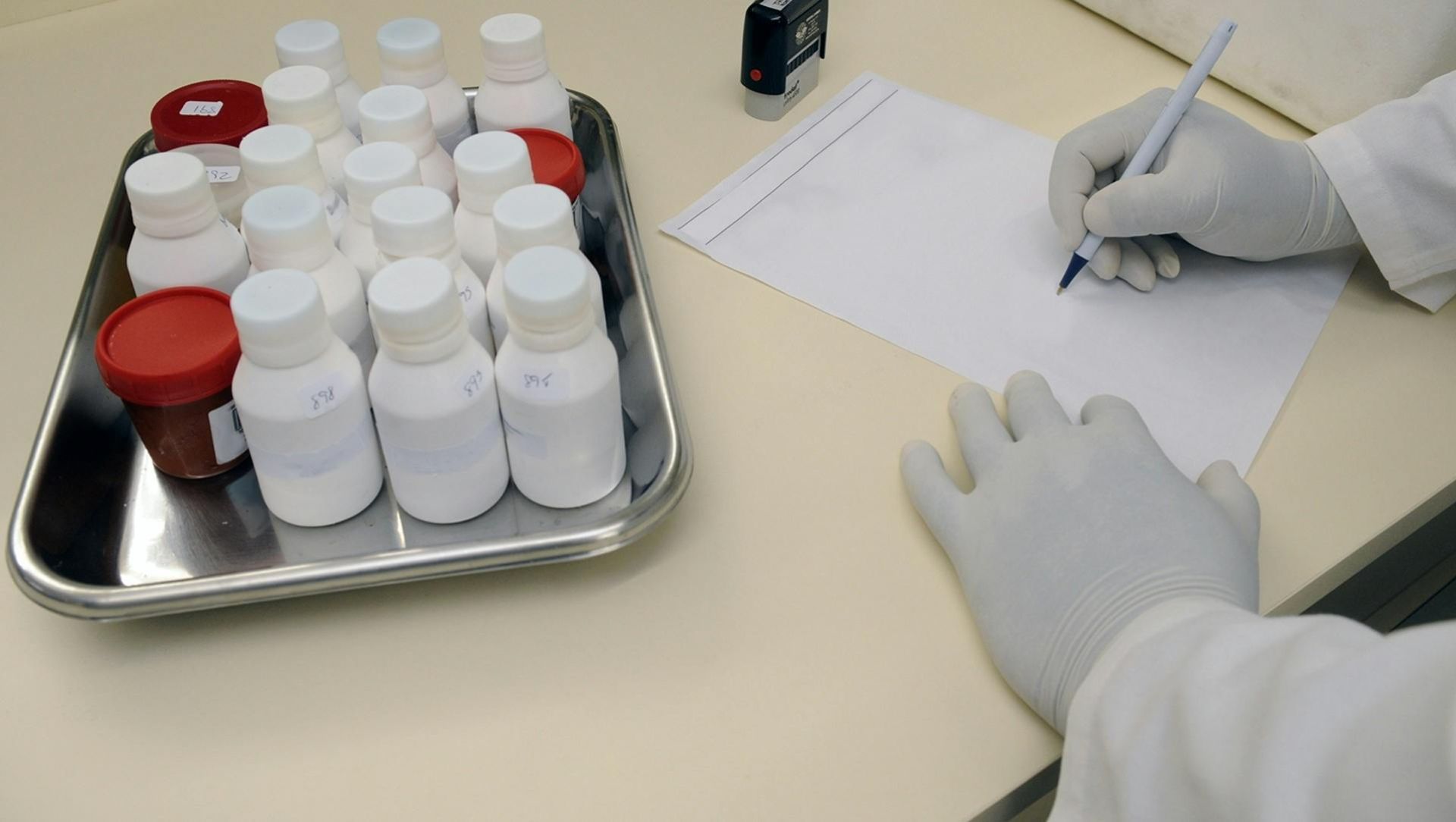 Laboratory technician writing report with samples in a medical lab.